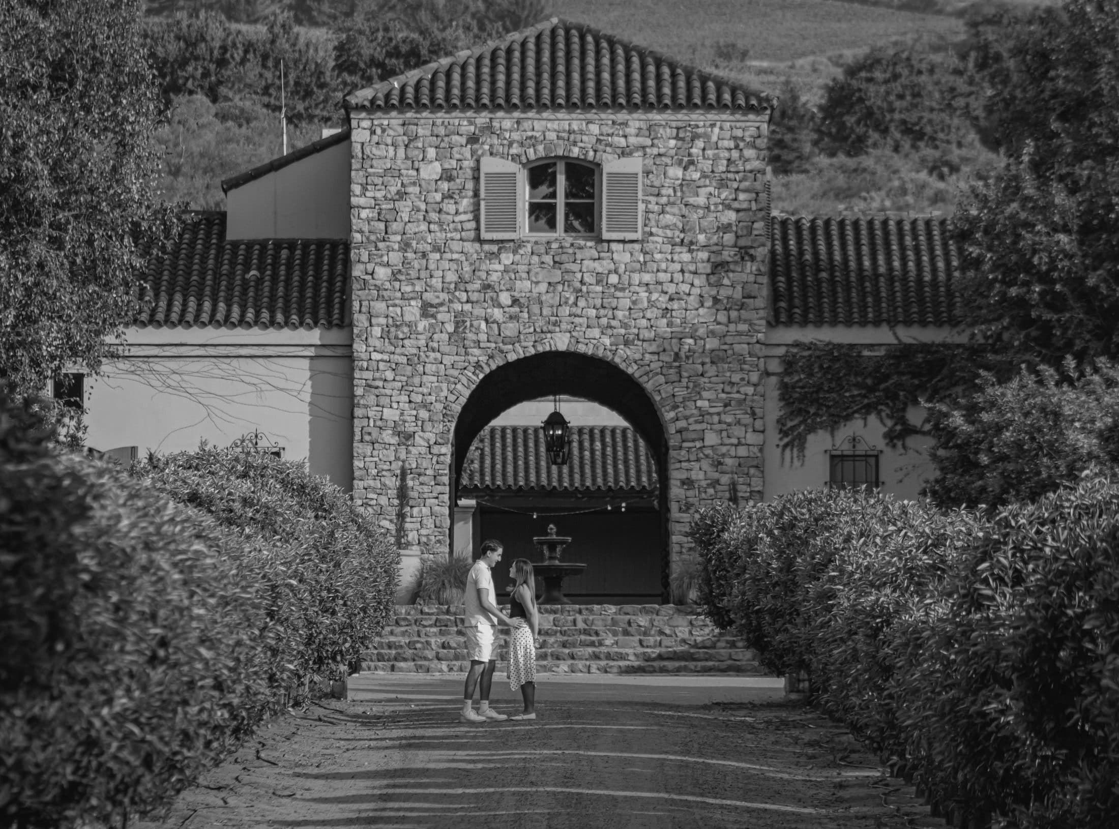Black-and-white photograph of the couple beneath a stone archway